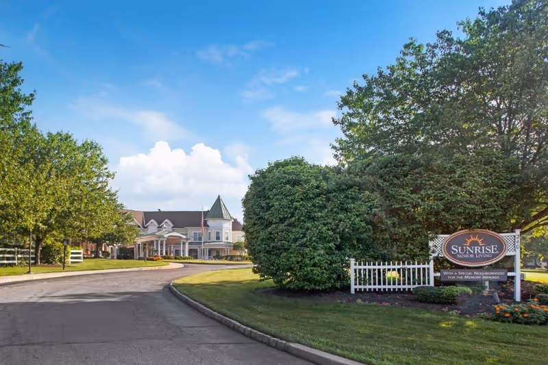 Driveway and landscaped entrance leading to the Sunrise of Westfield senior living building with a Sunrise Senior Living sign.