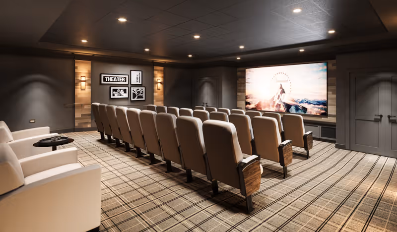 A cozy senior living facility theater room with rows of beige cushioned seats facing a large screen displaying a movie scene. The room has a patterned carpet, dim lighting, and framed pictures on the wall with a sign that reads 'THEATER'.