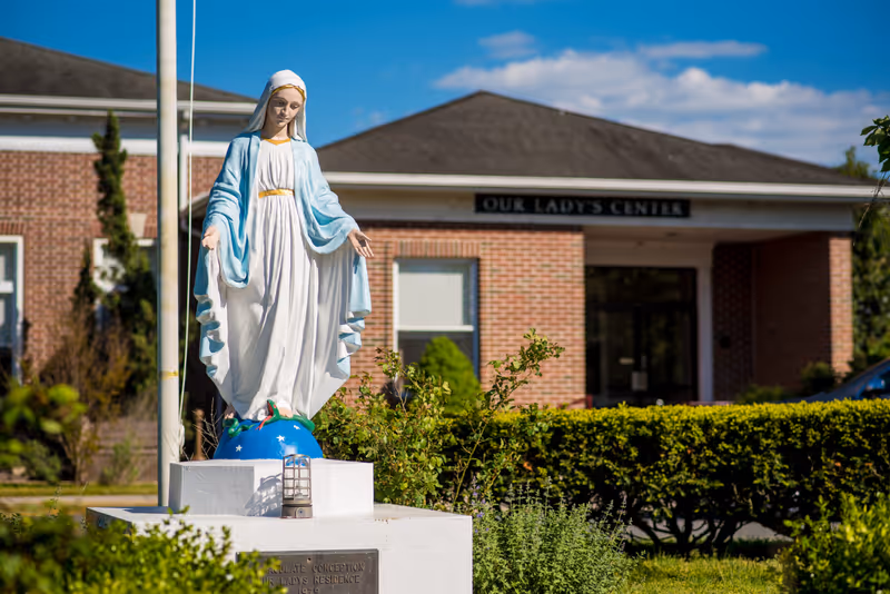 A statue of the Virgin Mary stands on a pedestal in front of the entrance to Our Lady's Center rehabilitation facility.