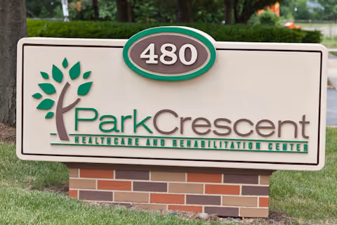 Outdoor sign on a brick base reading "480 Park Crescent Healthcare and Rehabilitation Center" with a tree logo in front of grass and trees.