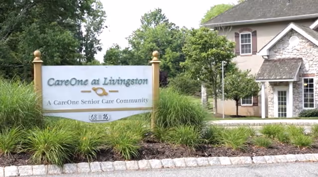 Entrance sign for CareOne at Livingston, a CareOne Senior Care Community, surrounded by greenery and landscaping with a building visible in the background.
