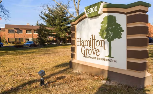 Outdoor monument sign reading 'Hamilton Grove Healthcare & Rehabilitation' with the address 2300 and the facility building visible behind it.