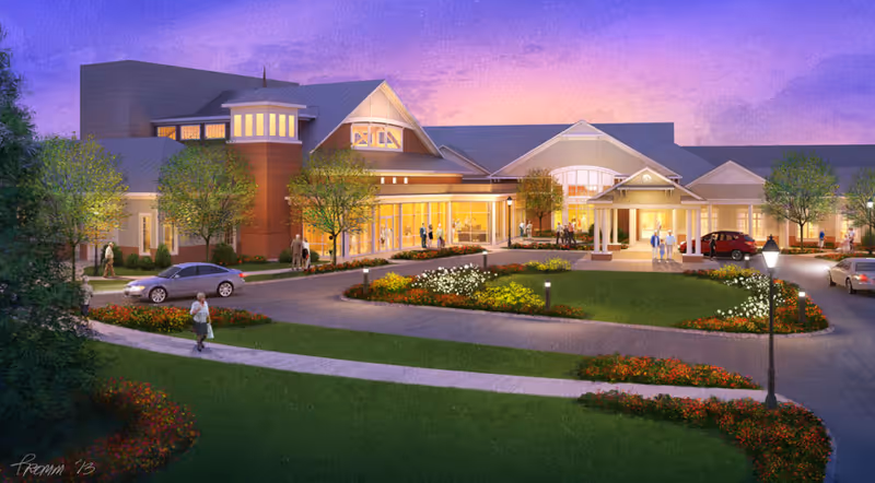 Exterior view of a senior living facility named Fellowship Village at dusk, showing a large building with warm interior lights, landscaped gardens, trees, a circular driveway with cars, and several people walking outside.